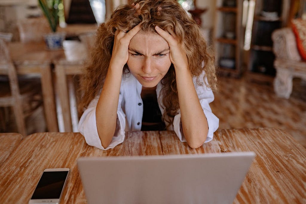 A woman looking defeated and frustrated in front of her laptop