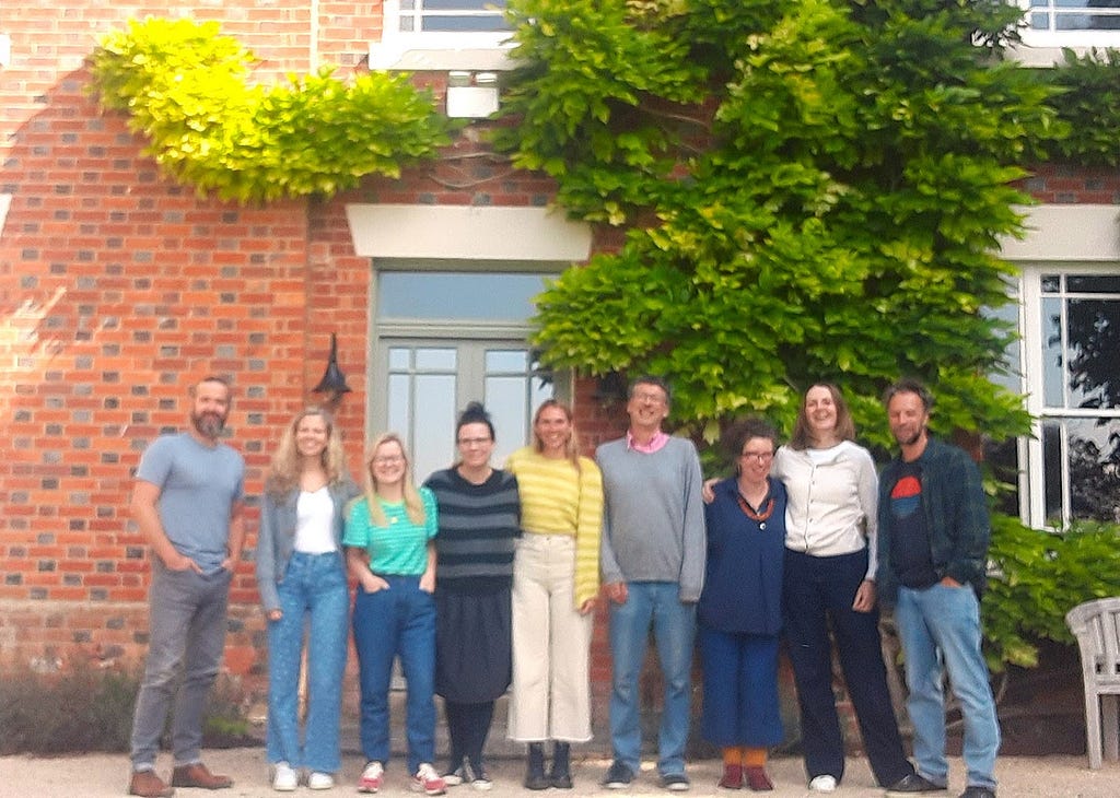 The nine members of the CAST team outside next to a house with greenery.