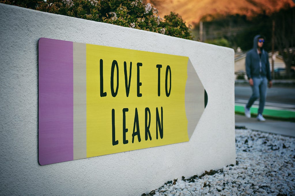 Large sign that says Love to Learn on a crayon shape