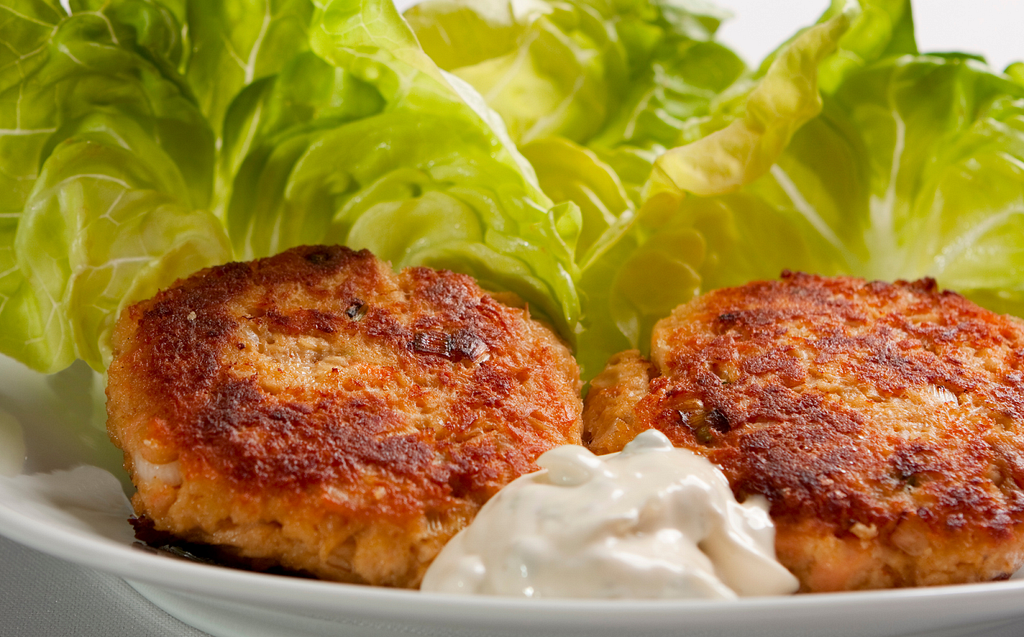 Plate with two Salmon Croquettes, lettuce leaves, and tartar sauce.