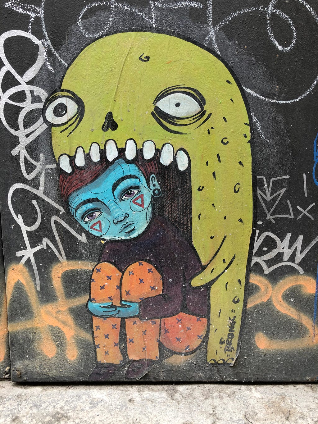 Graffiti art of a sad looking girl inside the mouth of a yellow monster.