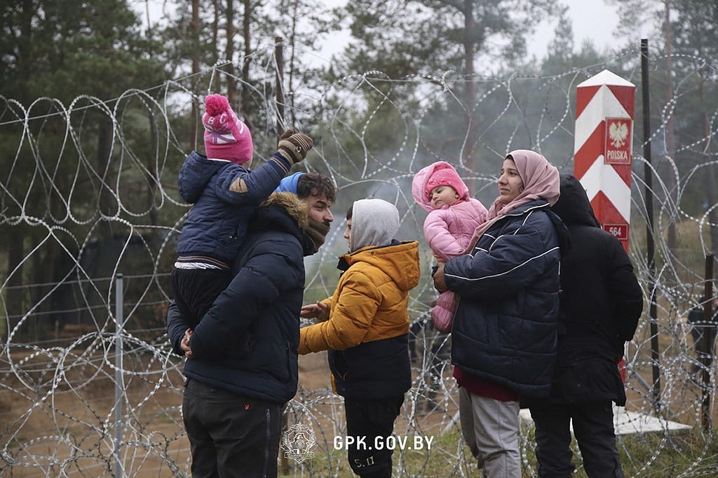 In this handout photo released by State Border Committee of the Republic of Belarus on Wednesday, Nov. 10, 2021, Migrants from the Middle East and elsewhere stand near near the barbed wire gathering at the Belarus-Poland border near Grodno, Belarus. Thousands of migrants have flocked to Belarus’ border with Poland, hoping to get to Western Europe, and many of them are now stranded at the frontier. (State Border Committee of the Republic of Belarus via AP)