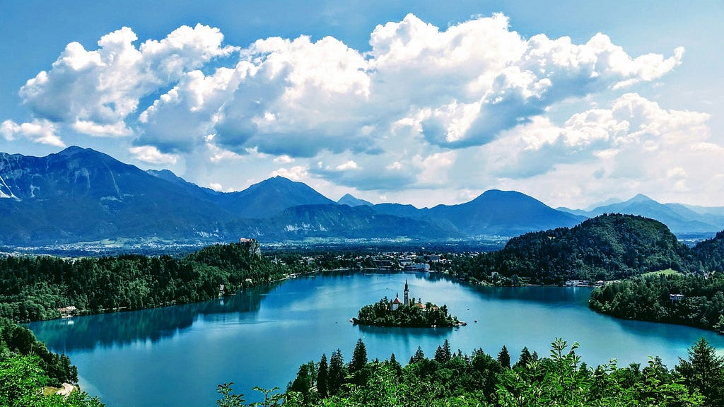 Island castle with bright blue water surrounding it and bountiful trees surrounding