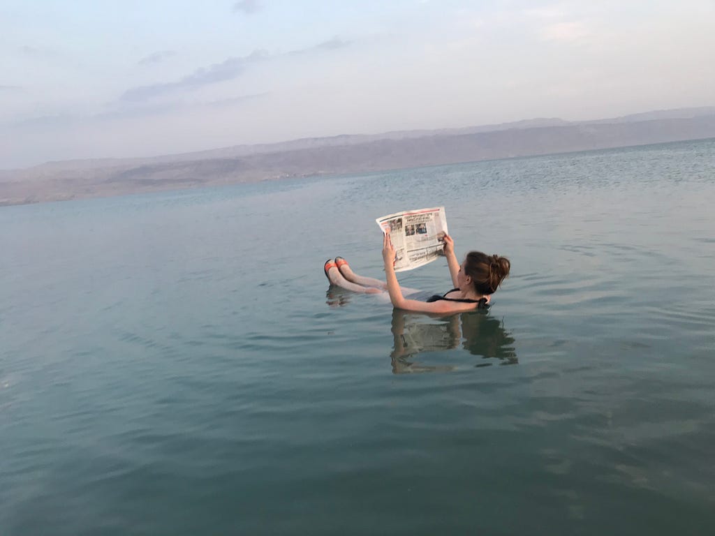 A woman reading a newspaper in the middle of the sea