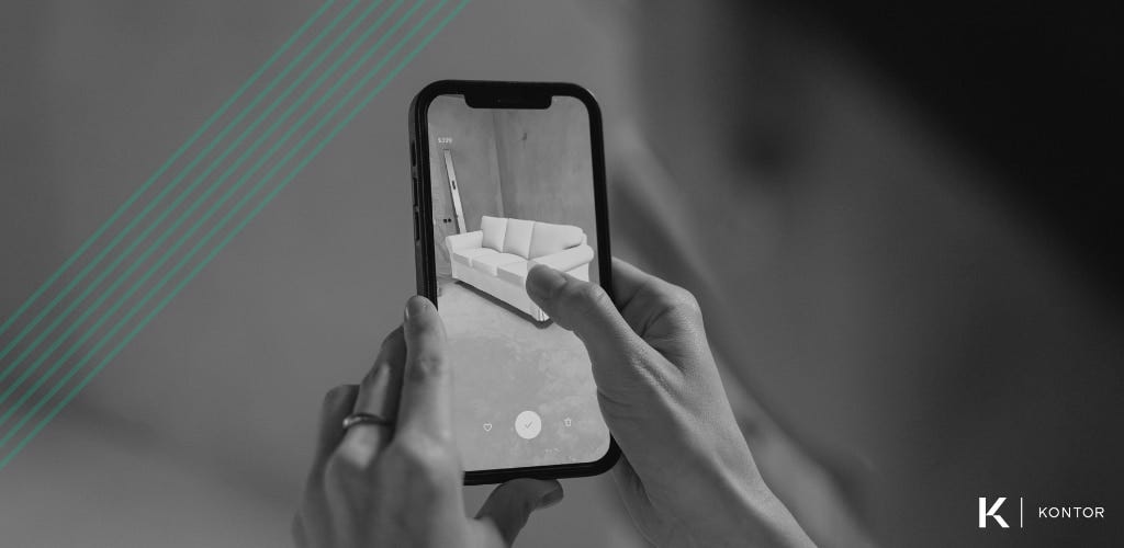 Black and white image of a person holding a smart phone using an AR application to visualize a new sofa in their home. Over the image are green diagonal lines. In the bottom right is the Kontor logo.