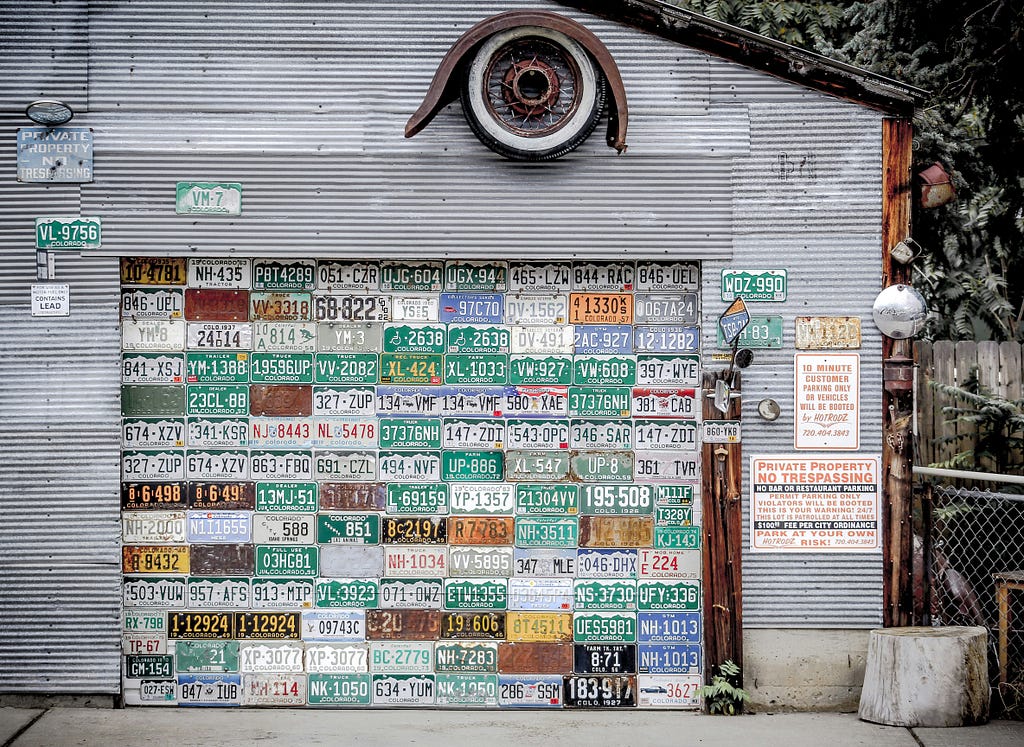 a gray house with the garage door covered with license plates