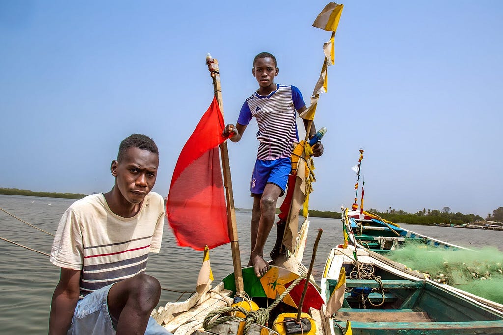 Two men in a small boat with a red flag.