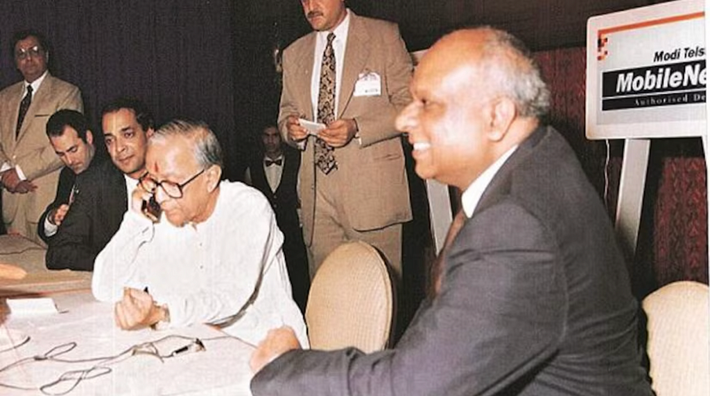 An old man talking on phone with all the politicians sitting near him in a comittee