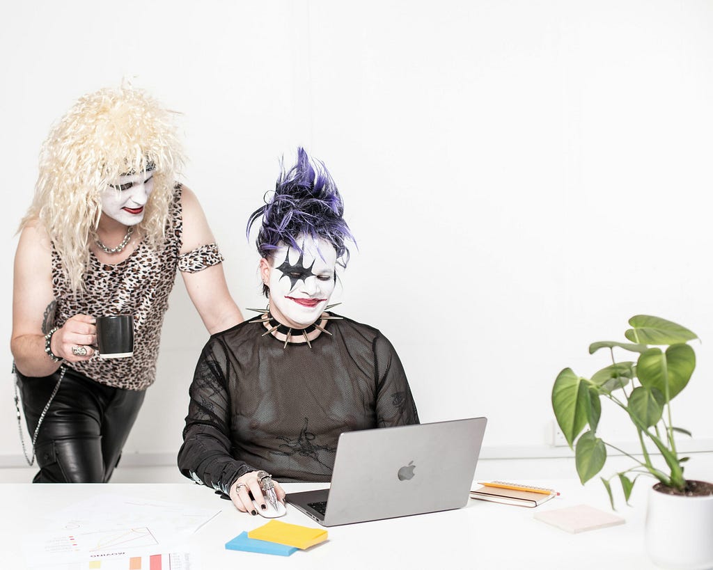 People in office set-up in fancy dresses and stylised make-up