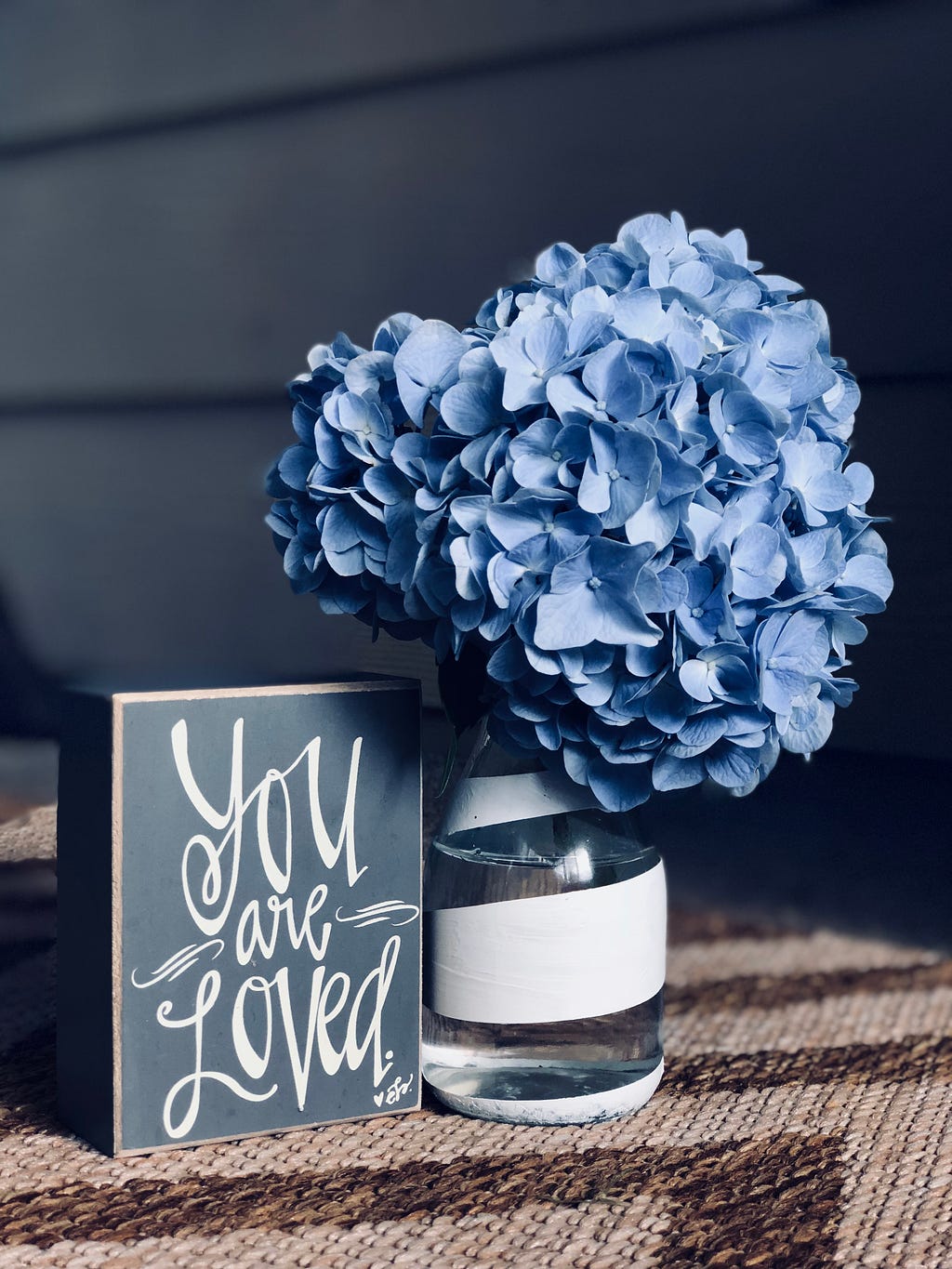 A tiny vase with blue flowers, and a card kept right next to it saying — You are loved.