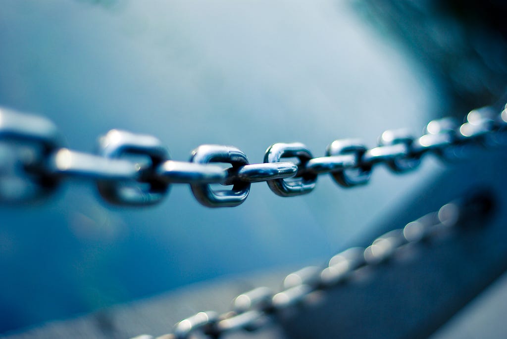 Interconnected steel chain links visually represent a linked list data structure, where each link serves as a node holding individual data and a reference, or ‘pointer,’ to the next link/node in the sequence.