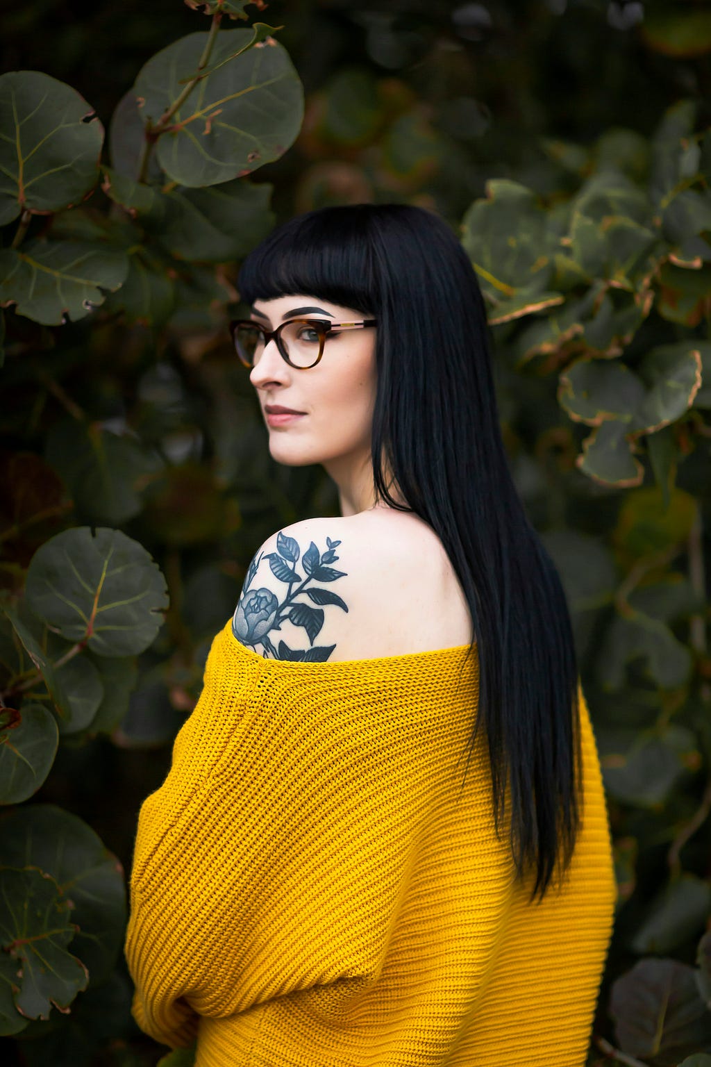 woman with tattoo on her shoulder surrounded by nature