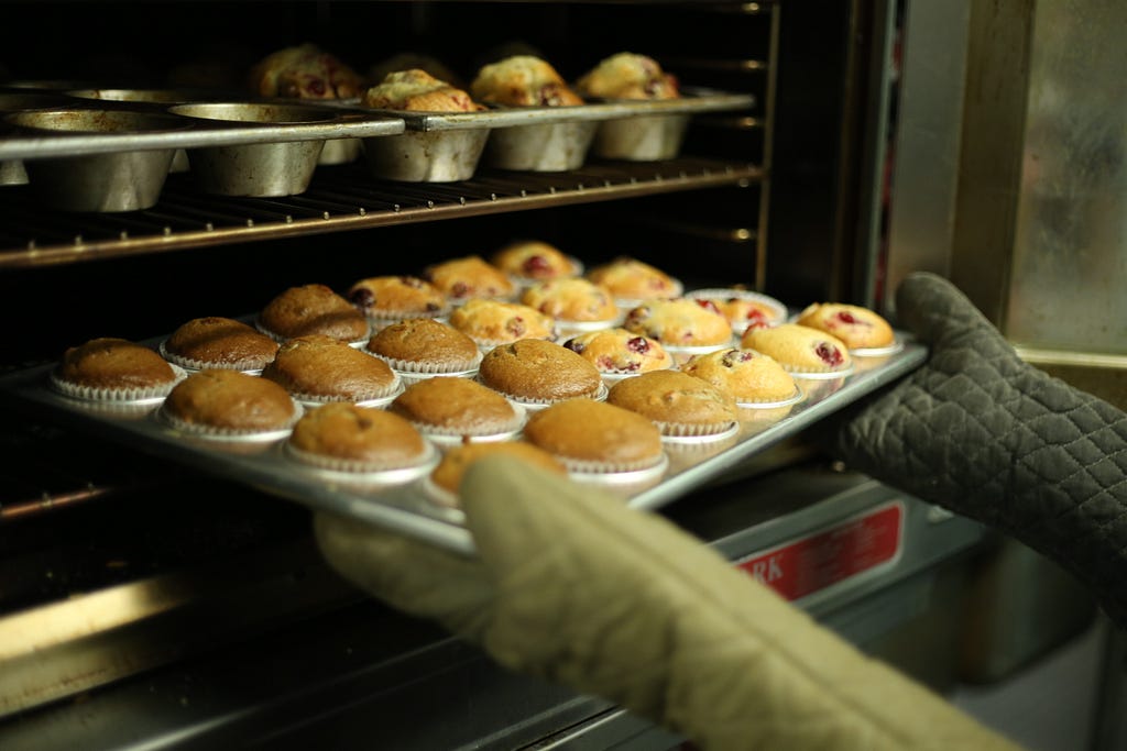 small business bakery taking muffins from an oven