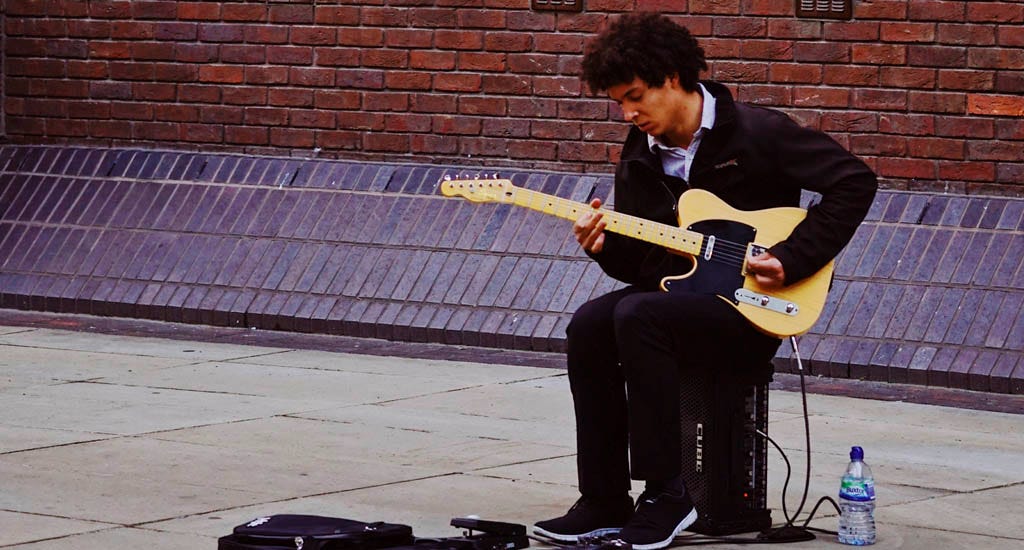 Indie artist playing guitar on street