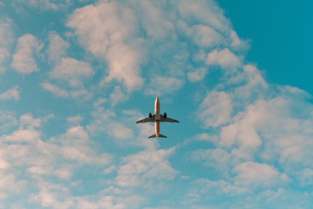 Bottom photo of a plane in flight in a pink and blue sky