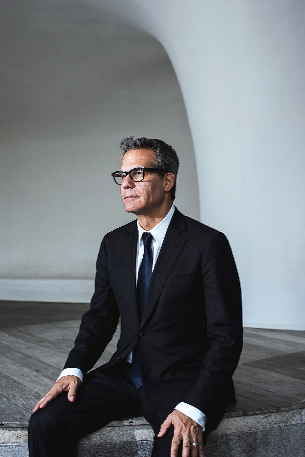 Image of man with glasses sitting in a suit