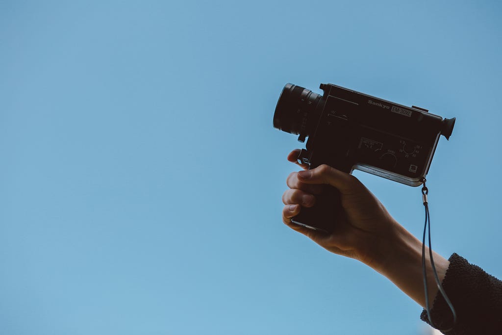 A person’s hand holding a camcorder up to the sky