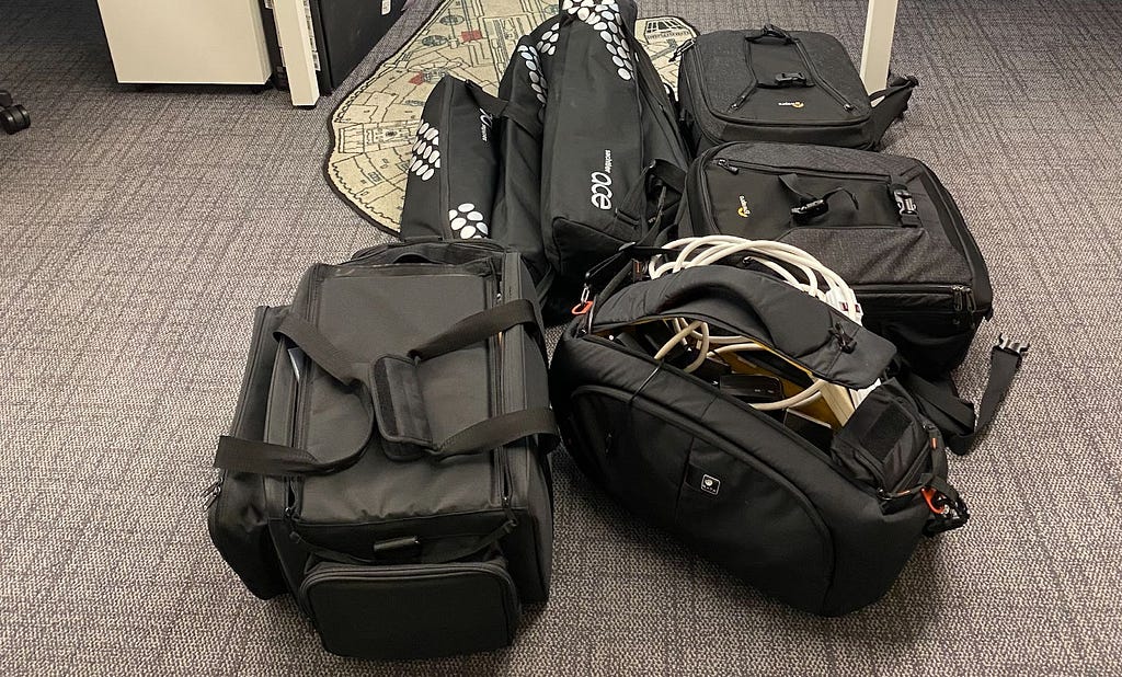 A pile of black nylon bags with some visible filming equipment