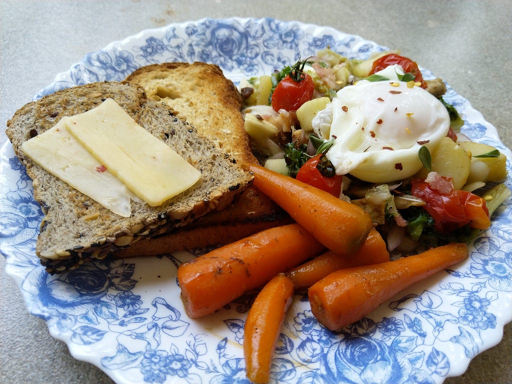 A Western-looking breakfast with eggs, bread, cheese and carrots