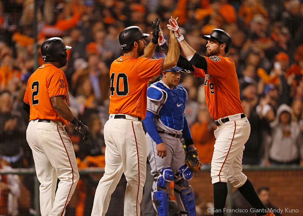 Denard Span and Madison Bumgarner high five Brandon Belt after scoring on a home run he hit in the sixth inning.