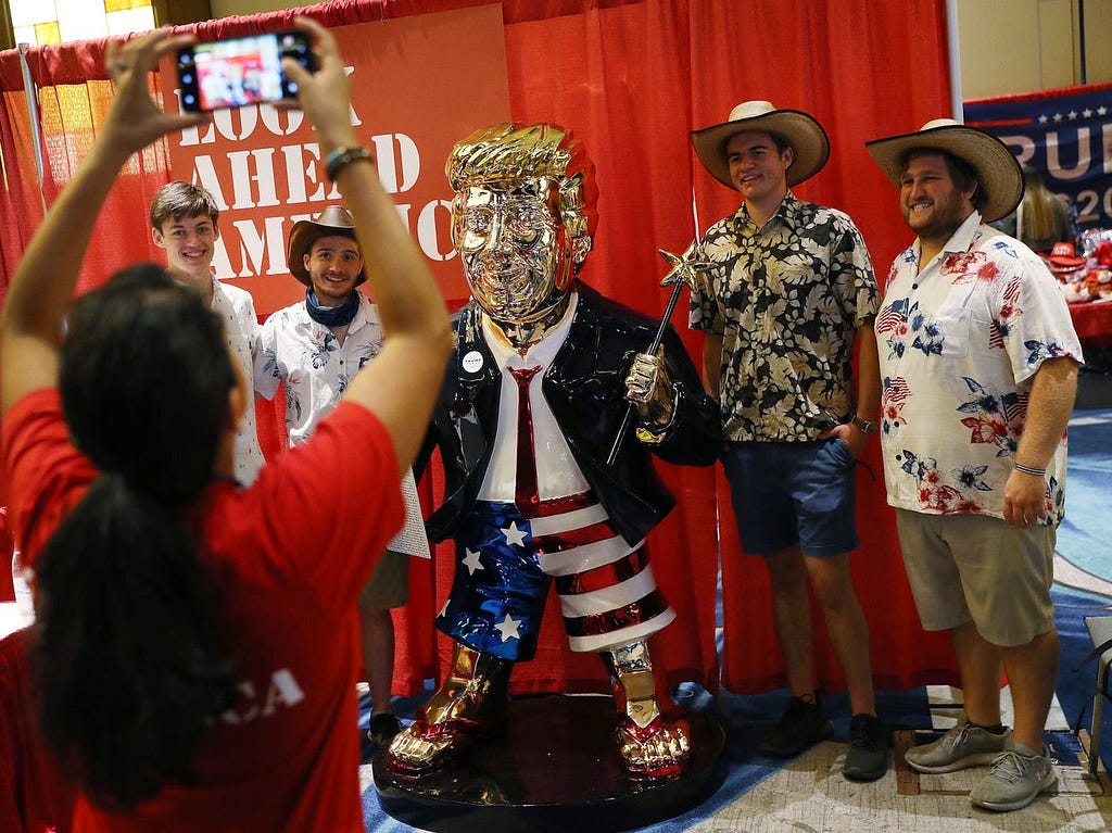 People take a picture with former President Donald Trump’s statue on display at CPAC.