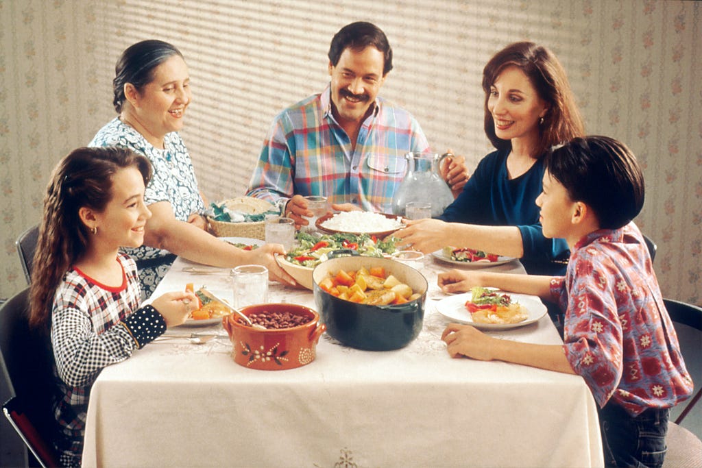 pic of 5 family members sitting at a dinner table- having a meal together.