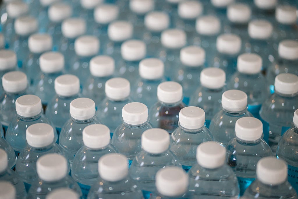 Rows of evenly distributed bottles of water showing the top of the water bottle and the bottle cap