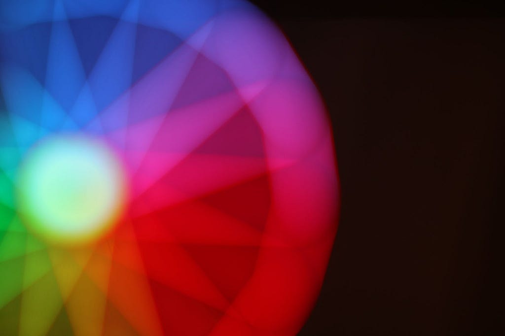 A photo of an out-of-focus, multicoloured wheel, representing a cycle with a full spectrum of considerations