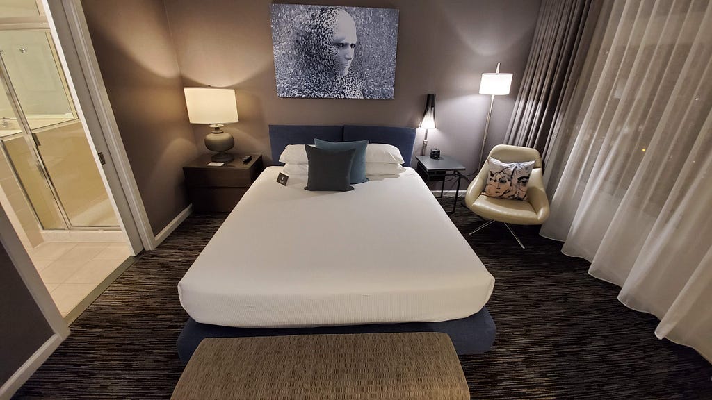 A clean hotel room showing a well-made bed and nice furnishings.