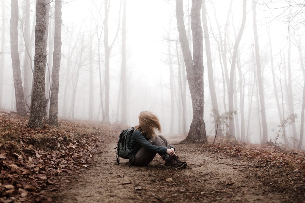 girl sitting alone in a foggy forest