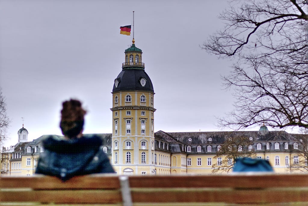 A woman sitting on a bench in front of a monument in Karlsruhe