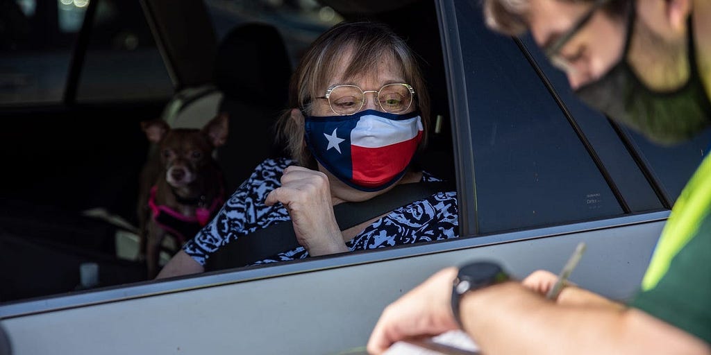 A poll worker helps a voter at a mail in ballot drop off location on October 13, 2020 in Austin, Texas.