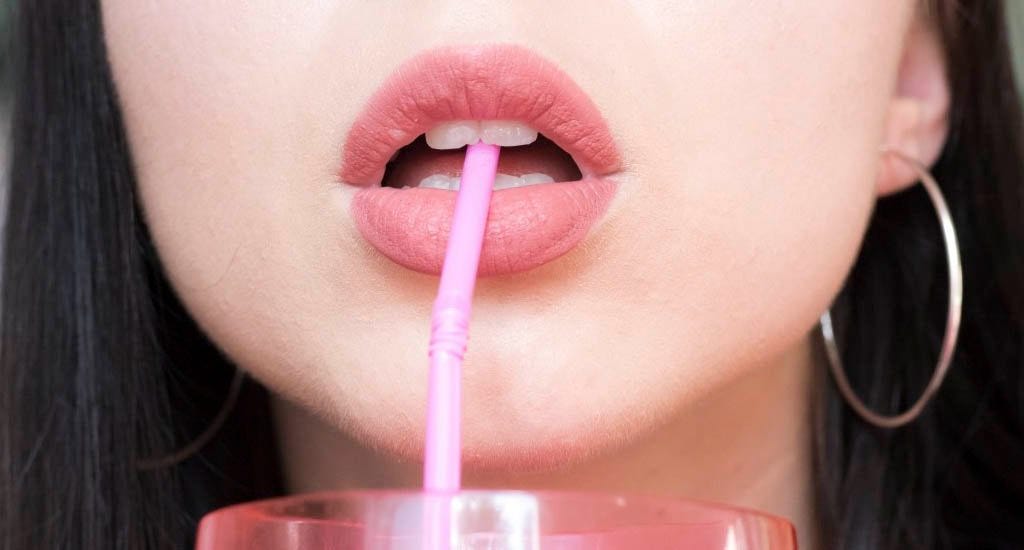 Woman drinking collagen drink through straw