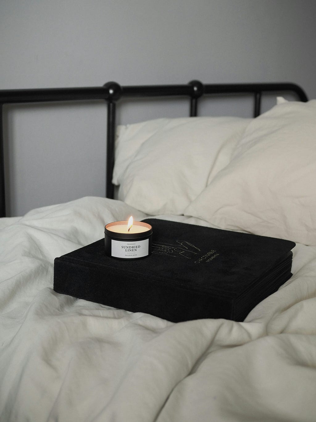 White bed and a book and candle on top of it.