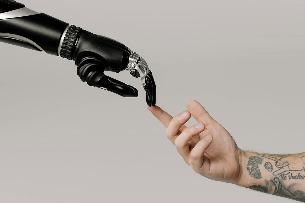 A robot hand reaching out to touch a human hand, representative of Michelangelo’s Creation of Adam painting