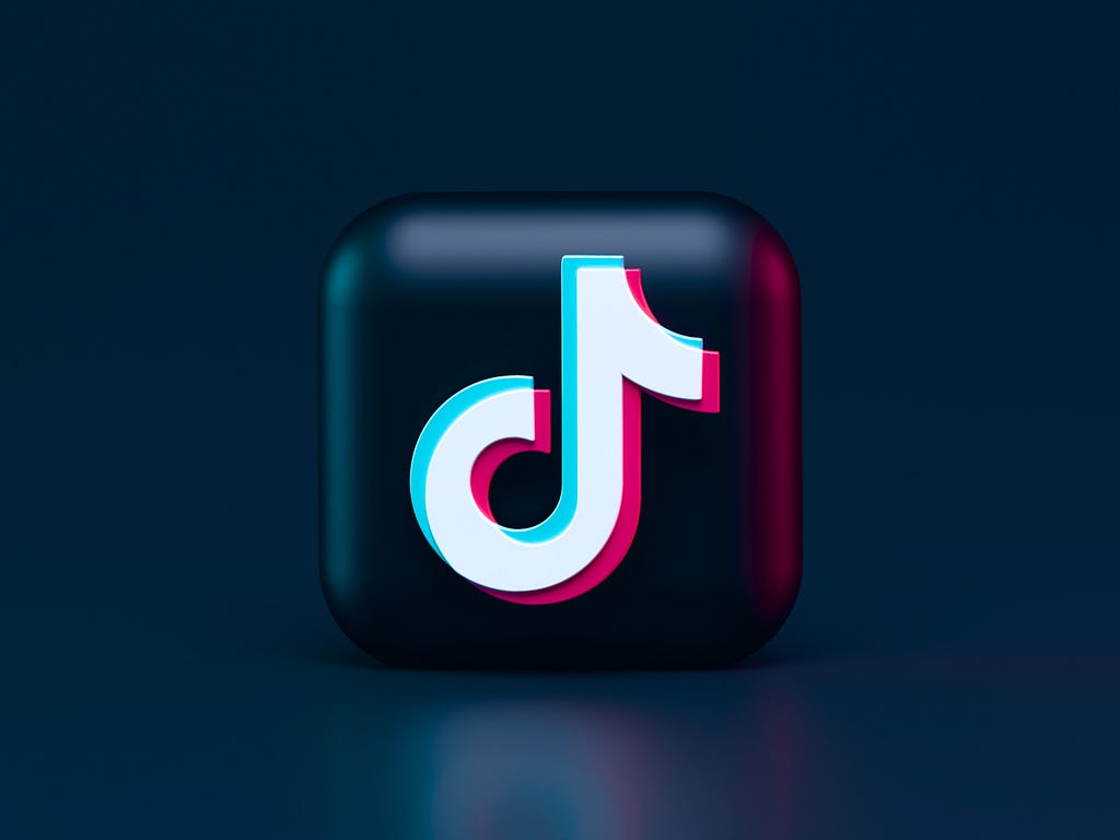 A 3D render of the TikTok logo and black button icon on a dark blue background