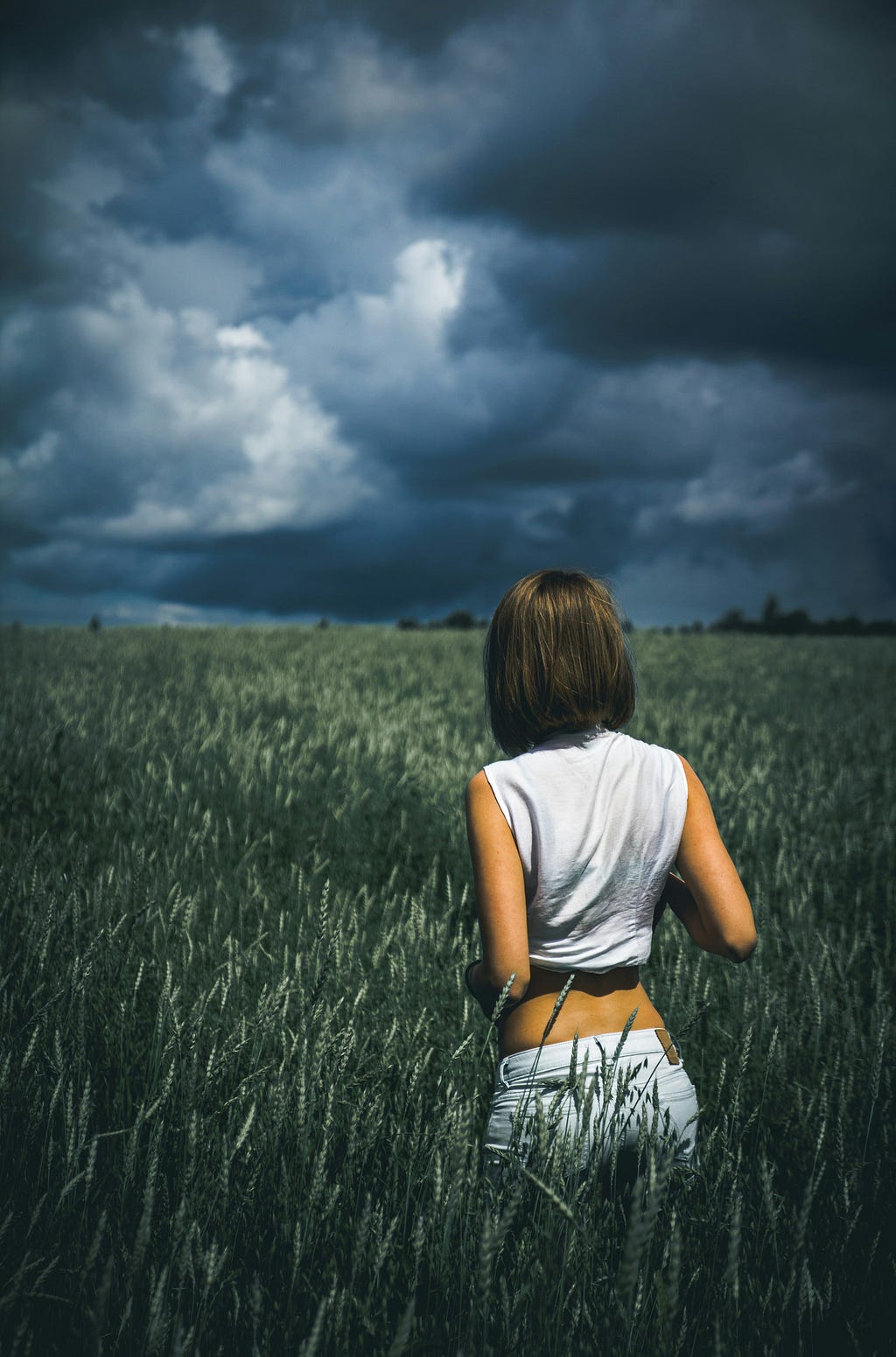 Looming of the clouds witnessed by a lady over a huge, mellow grassland.