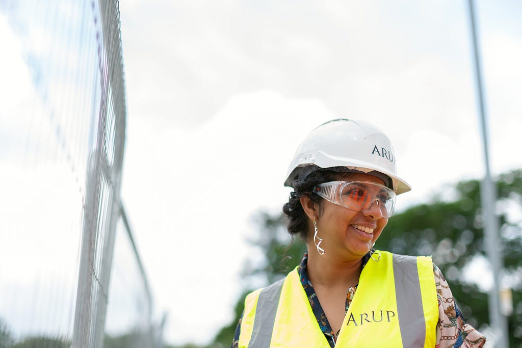 A woman in a construction outfit smiles