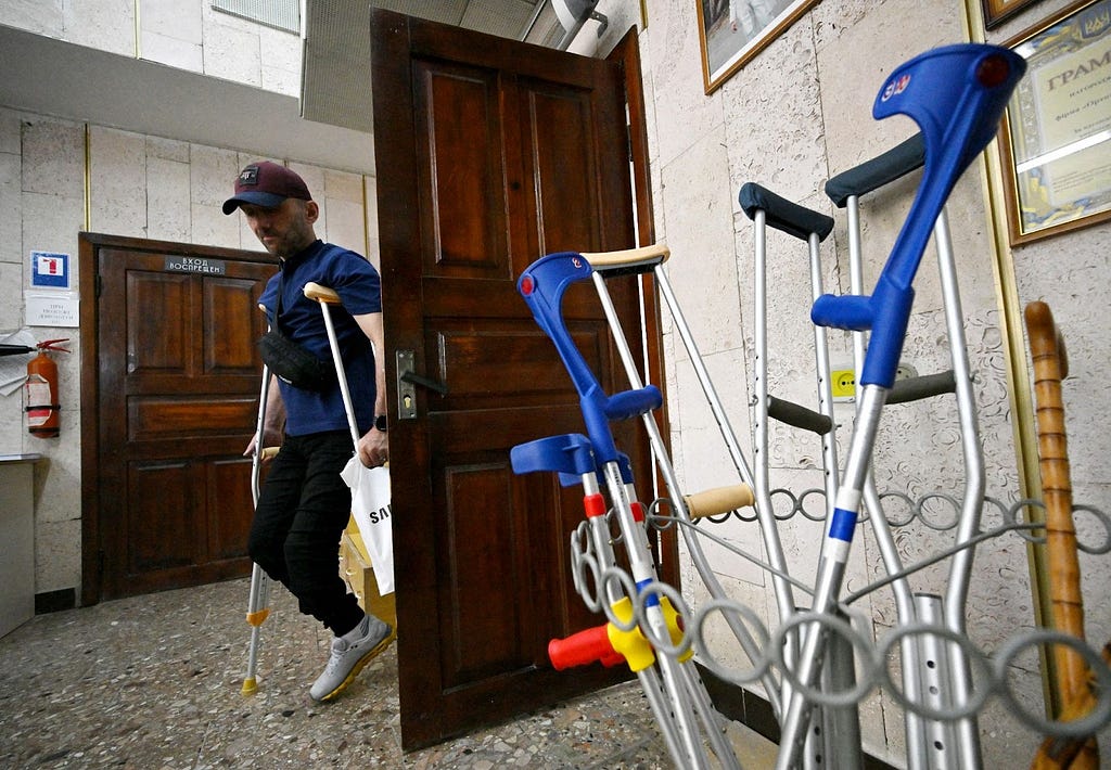 A man on crutches enters through a door and into a room that holds more crutches and other assistive devices.