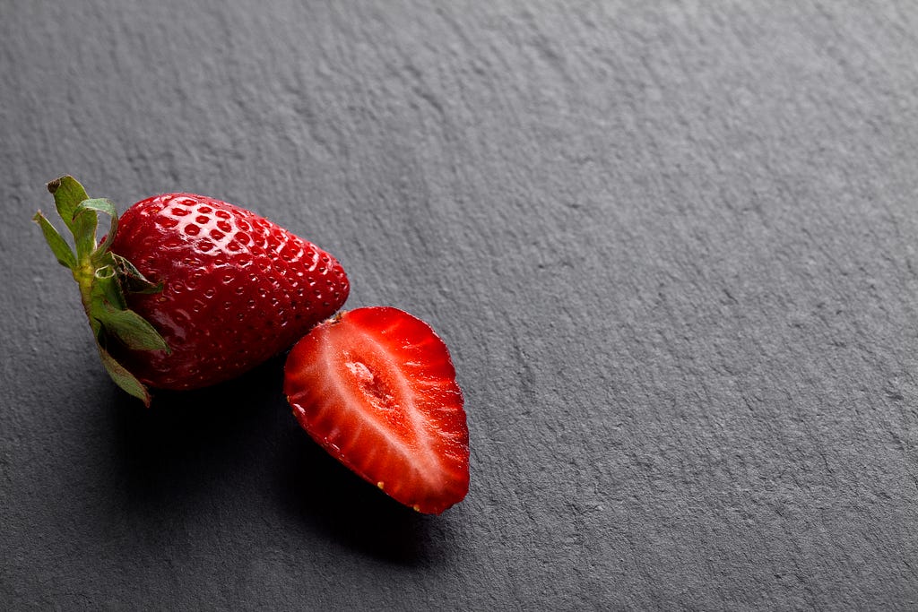 Strawberries against a grey, concrete background.