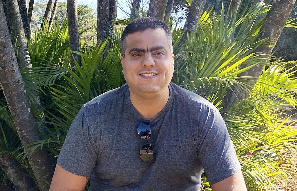 Arthur Rogel, this post's author, in front of some trees in a sunny day