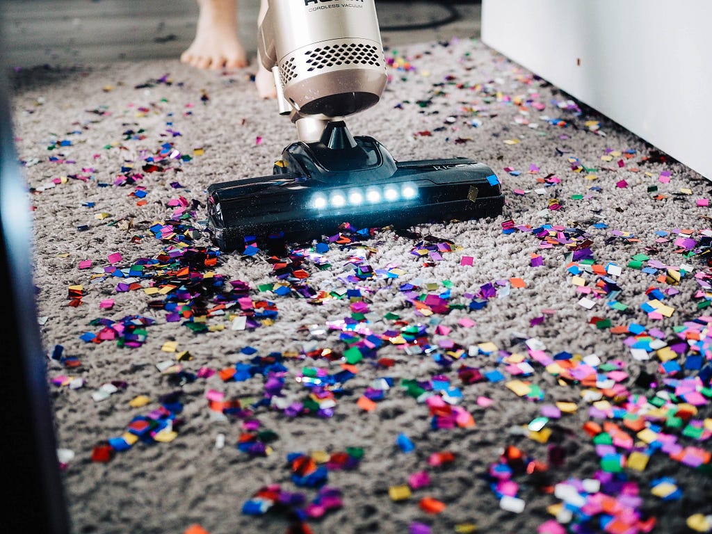 Someone is cleaning a carpet from confetti with a vacuum cleaner.