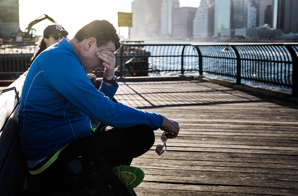 man rubbing eyes at lookout on the water // Photographer: Bruno Aguirre | Source: Unsplash