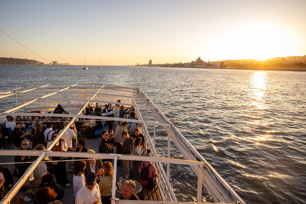 Attendees partying on the boat deck at sunset.