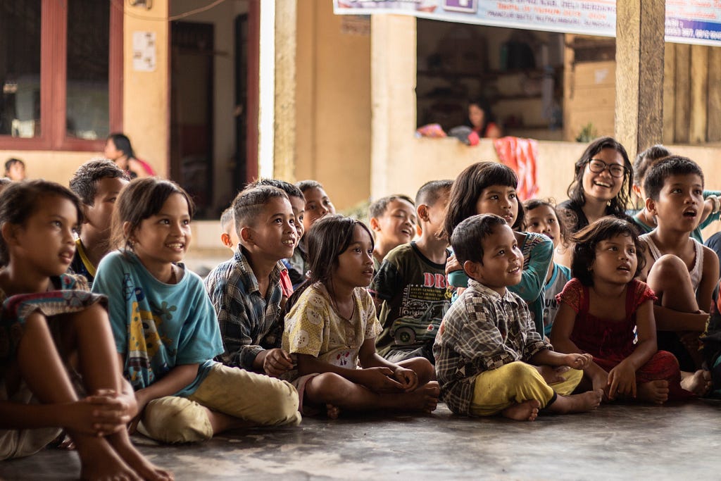A crowd of children seated on the floor, listening attentively