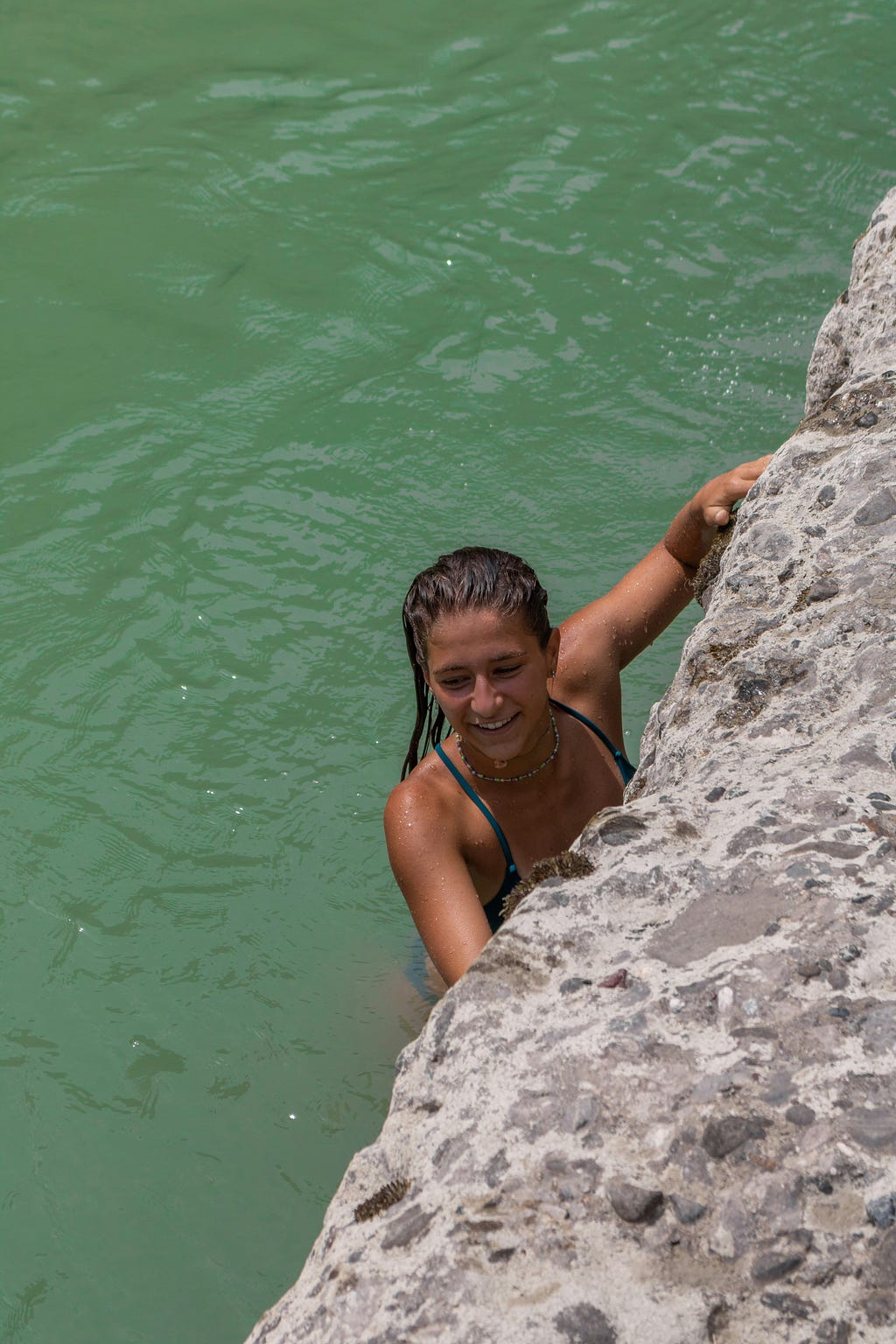 A lady clinging to the cliff with the sea below