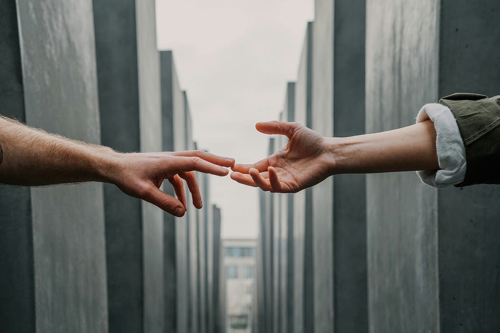 Two human hands with finger tips almost touching each other.