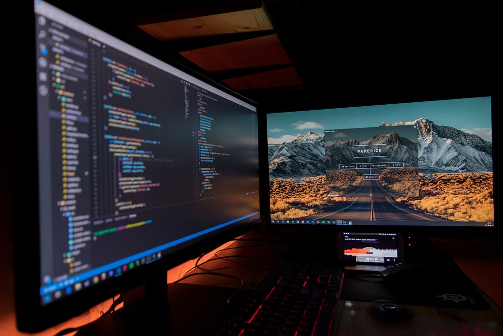 A desk with two monitors on