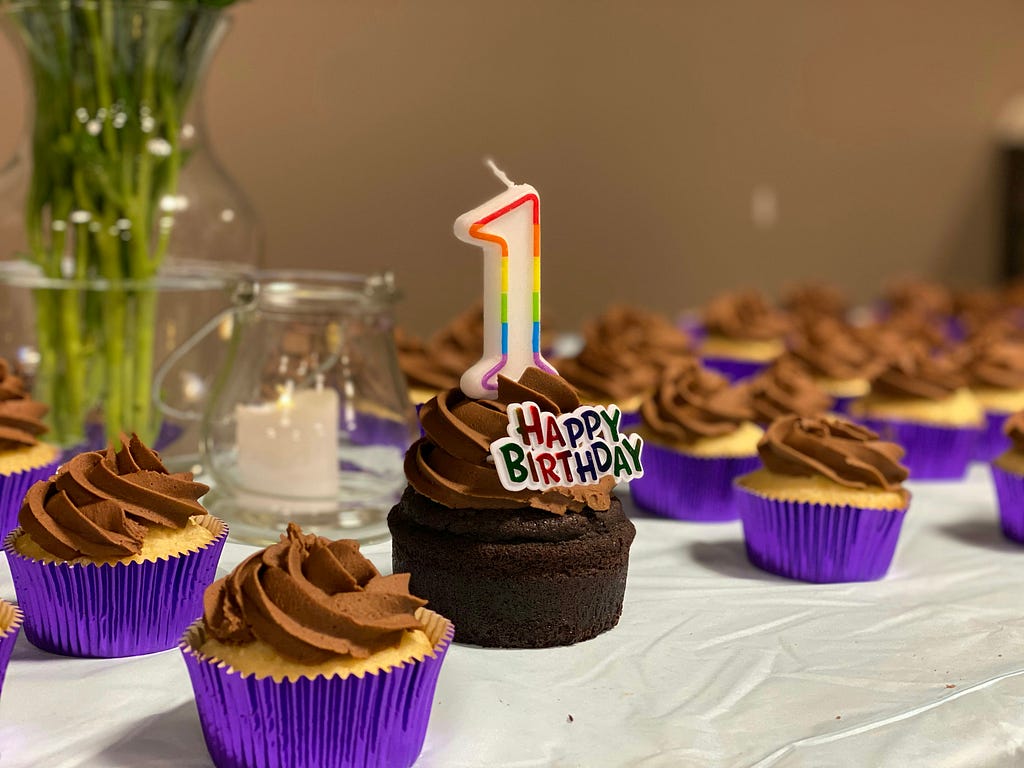 A table of birthday cupcakes, one of which has a ‘1’ candle and ‘Happy birthday’ decoration