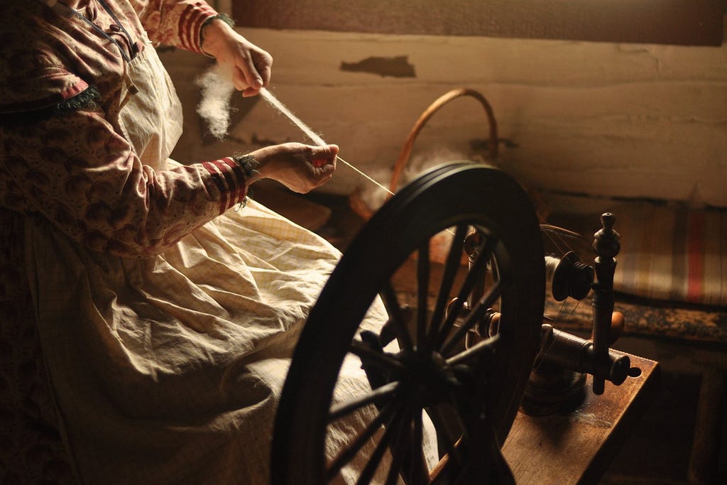 Woman spinning yarn on antique wheel